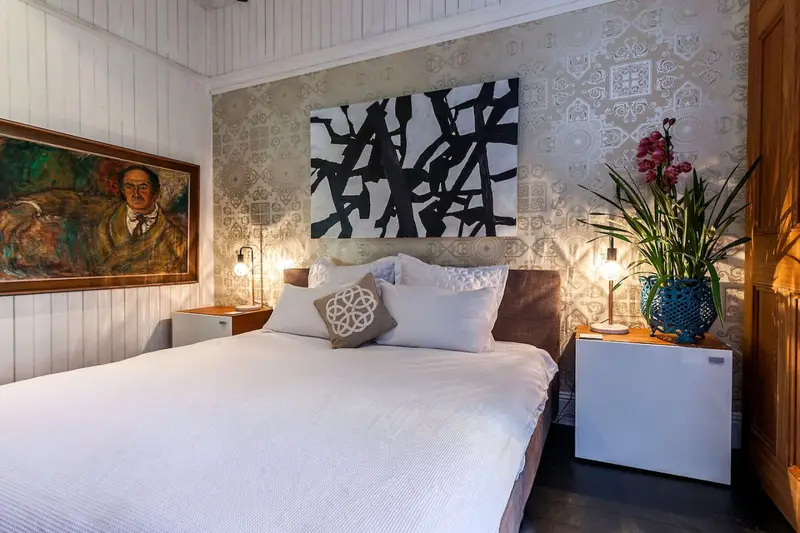 Bedroom with a portrait, patterned wallpaper and bedside lamps