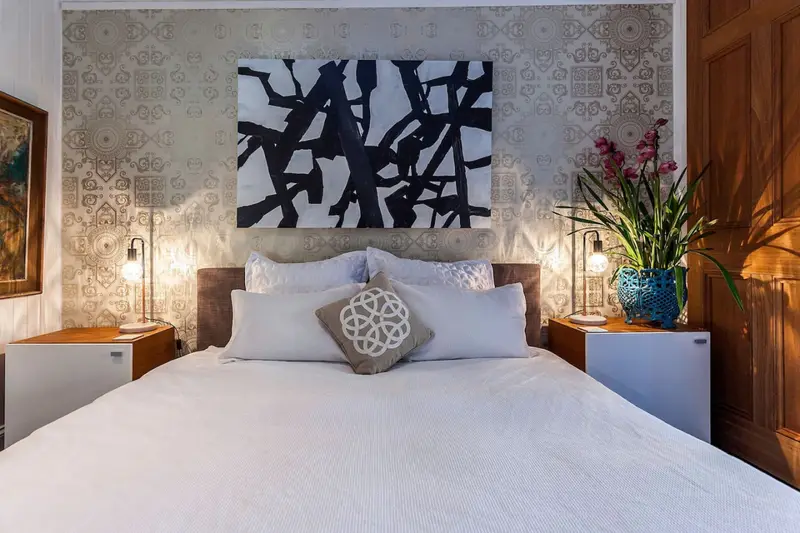 Guest bedroom with patterned wallpaper, brass lamps and orchids