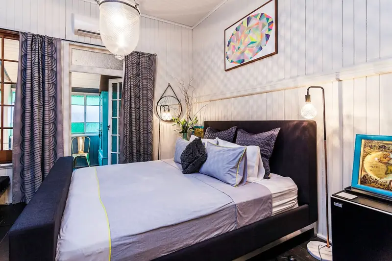 Bedroom with a dark upholstered bedhead and doors to the verandah