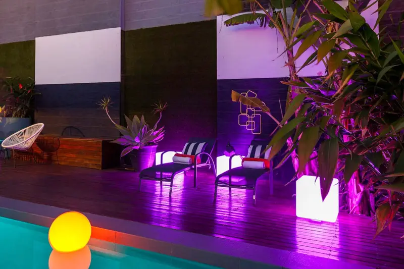 Sun loungers on the deck beside the pool, lit purple at night