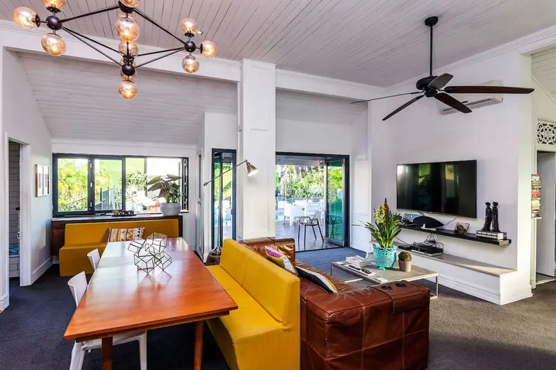 Living and dining room with a vaulted ceiling, brass chandelier and yellow banquette