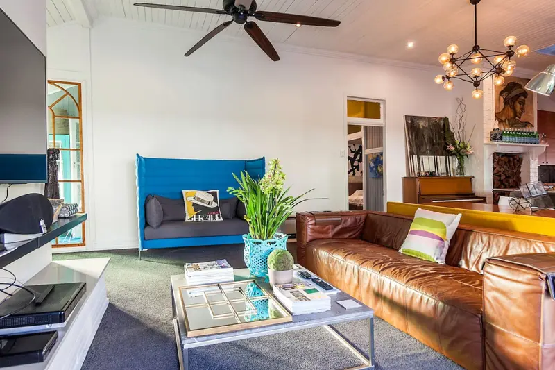 Second living room with a leather sofa, blue armchair and open fireplace