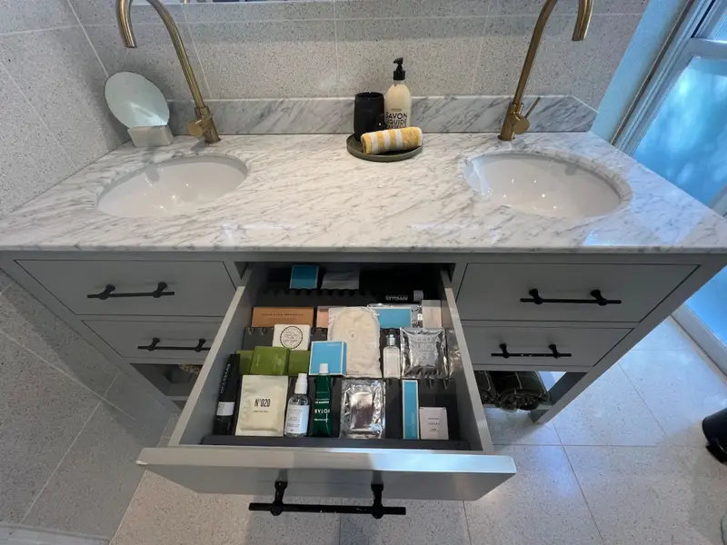 Guest toiletries laid out in a drawer beneath the marble vanity