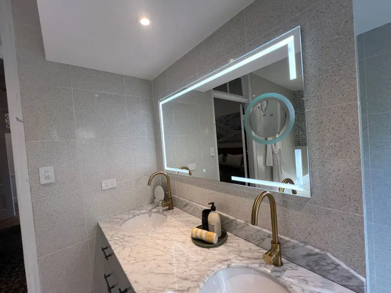 Double marble vanity with a backlit mirror and brass tapware