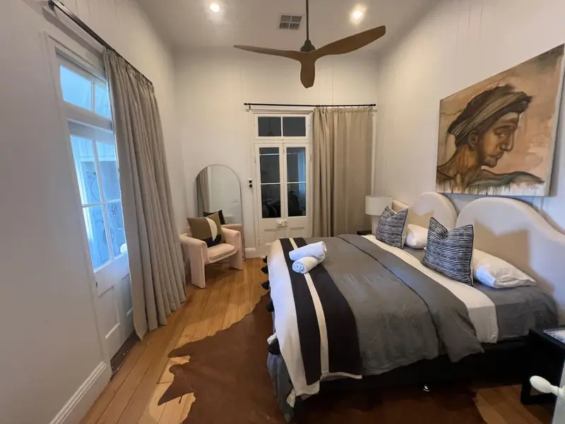Bedroom with a curved upholstered bedhead, artwork and french doors