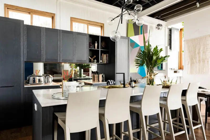 Black country kitchen with a marble island, brass tap and six bar stools