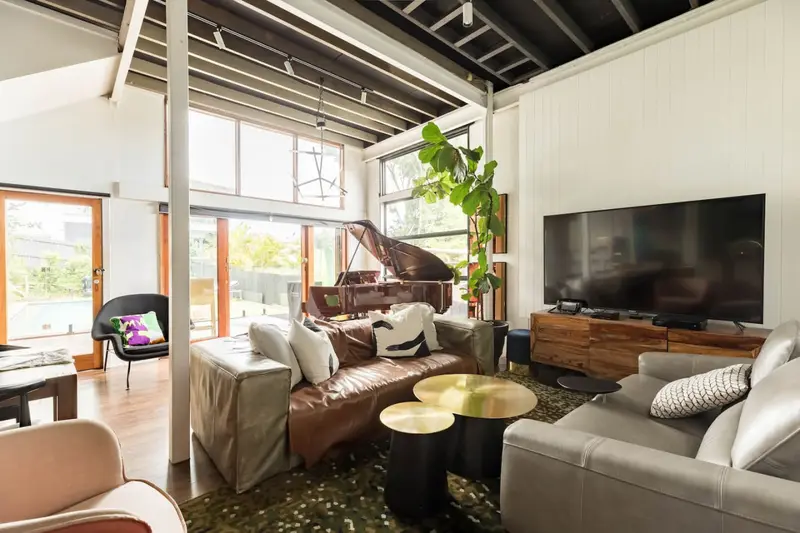 Living room with leather and linen sofas, a large television and the piano beyond