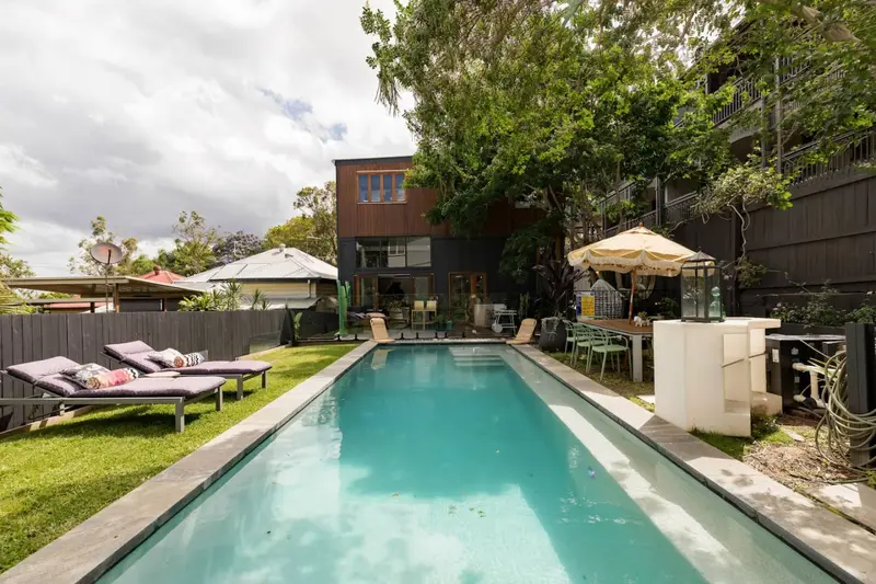 Lap pool seen from the far end, with loungers, umbrella and outdoor dining