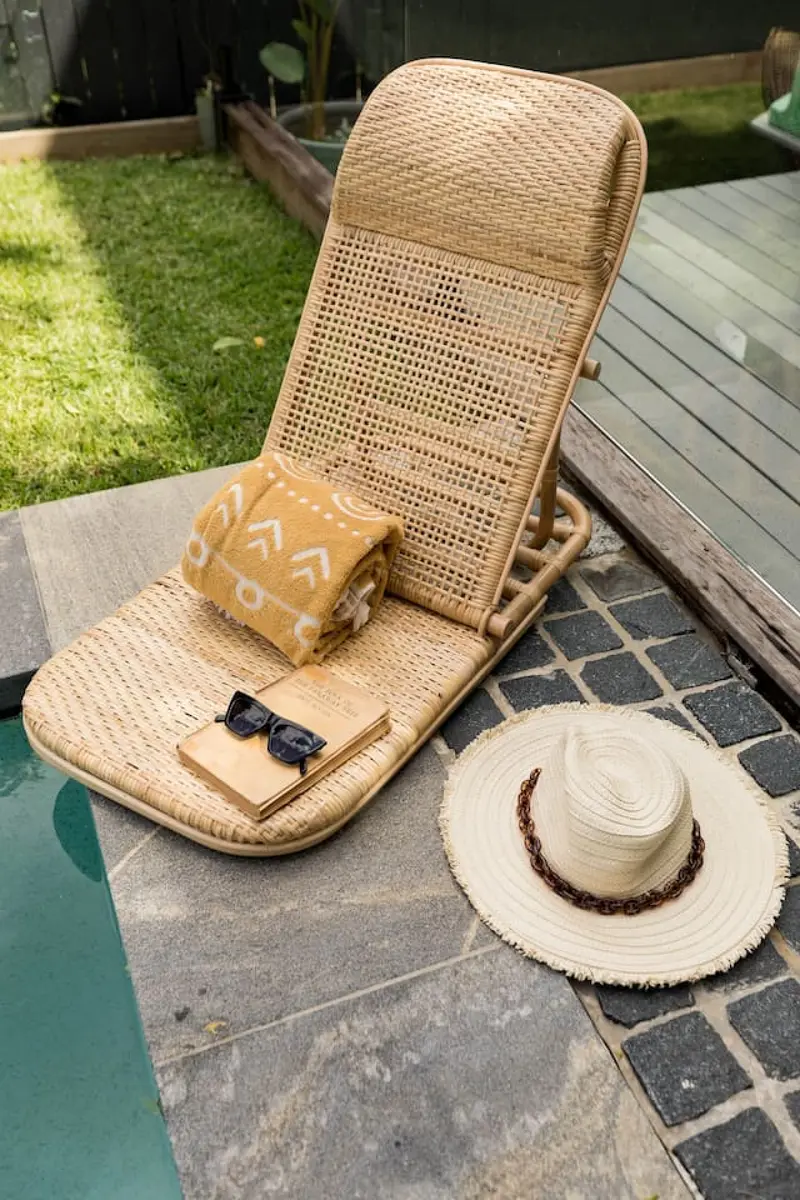 Rattan lounger, towel and sun hat on the bluestone pool surround