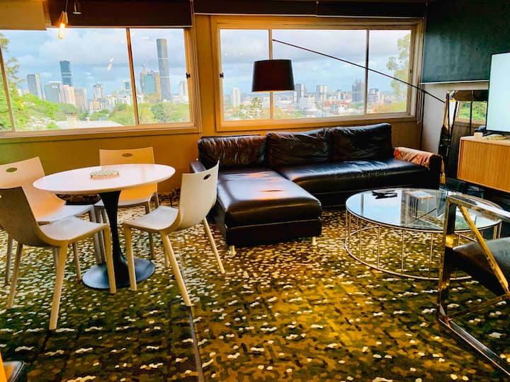 Open lounge and dining area with city views through wraparound windows