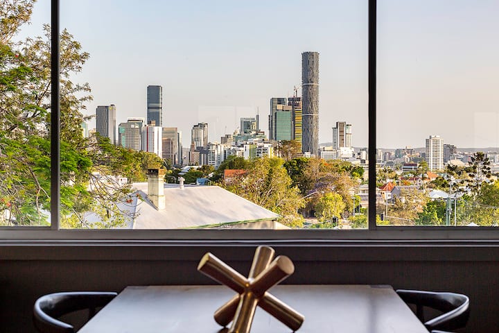 Dining table set against a picture window with the Brisbane skyline beyond