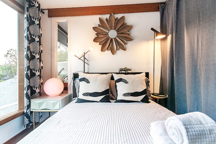 King bedroom with a sunburst mirror, patterned curtains and bedside lamps